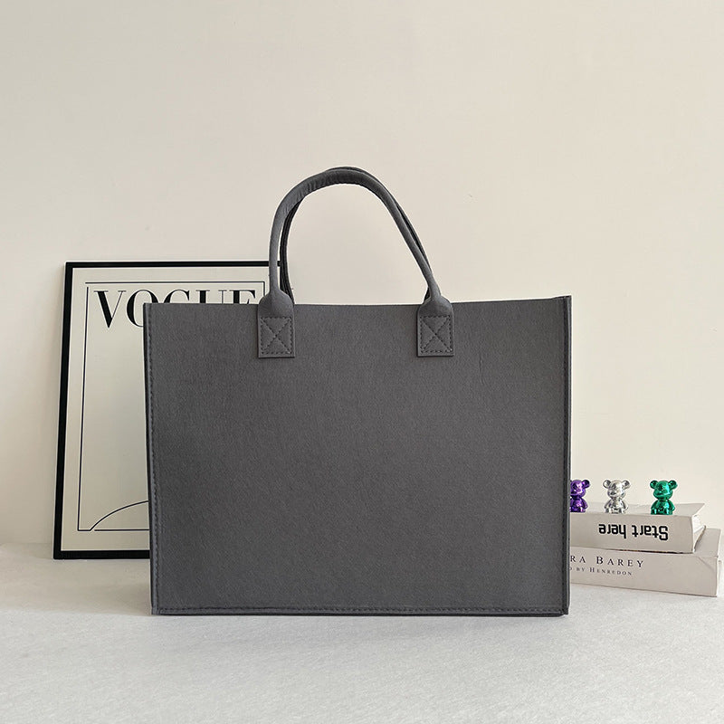 Structured felt tote bag with reinforced handles and organized interior Bowlift