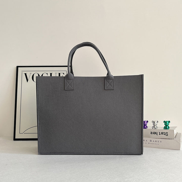 Structured felt tote bag with reinforced handles and organized interior Bowlift