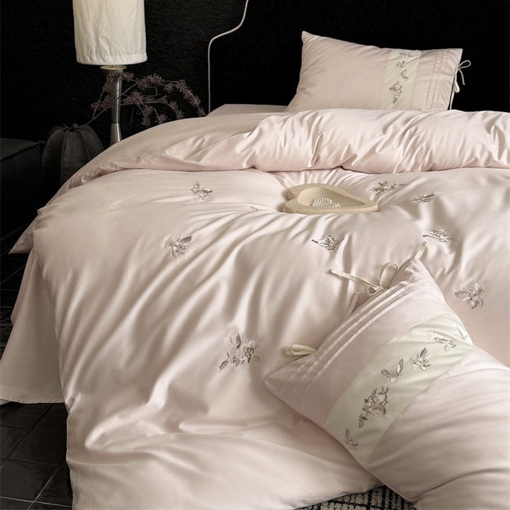 Luxurious satin bedding set with embroidered floral appliqués and bolster Bowlift
