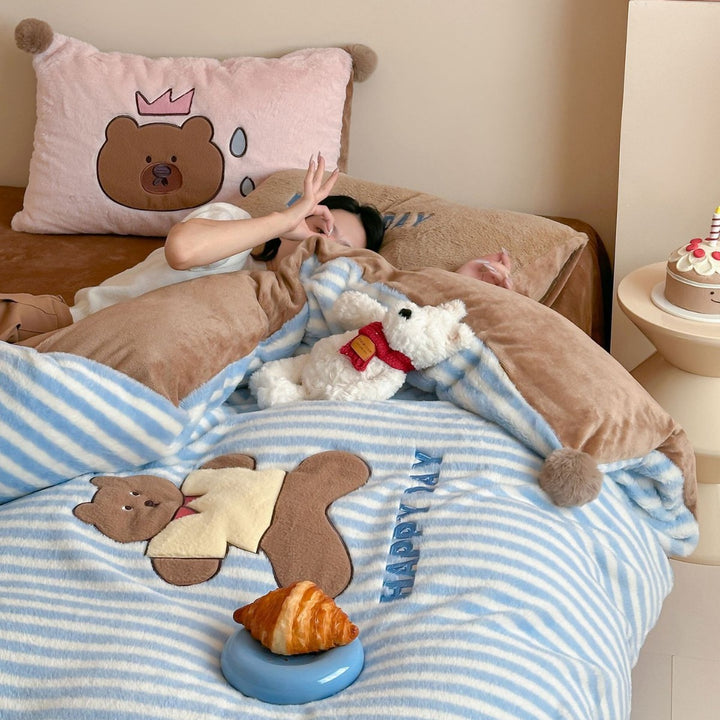 Striped plush throw blanket with decorative pom poms and appliqués