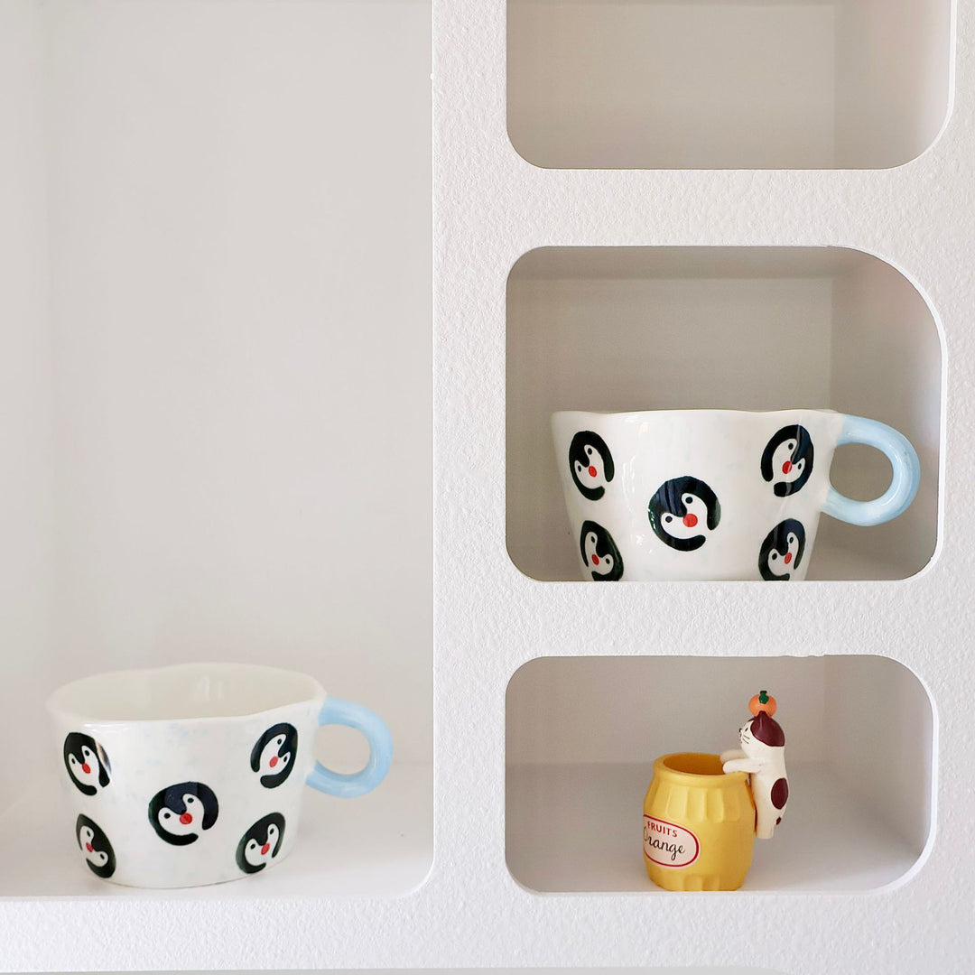 Ceramic coffee mug with hand-painted penguin designs and ergonomic handle