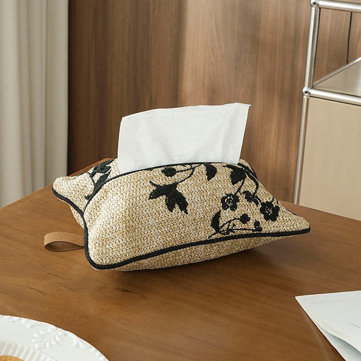 Woven tissue box cover made of straw with embroidered floral design and carrying strap